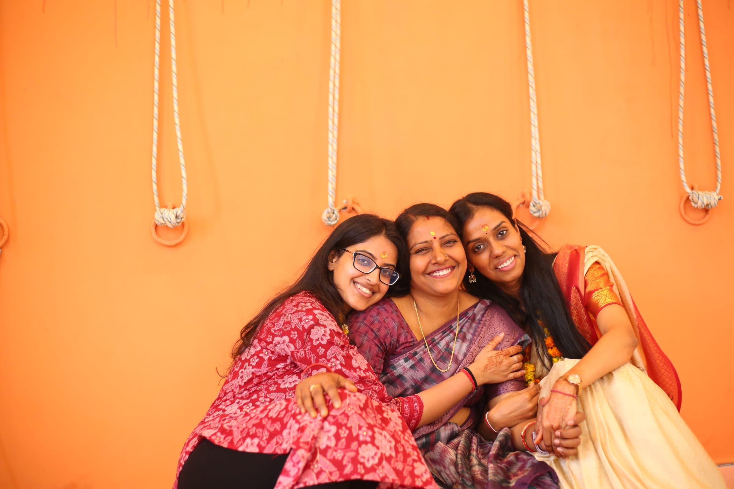 Three friends laughing against the orange wall