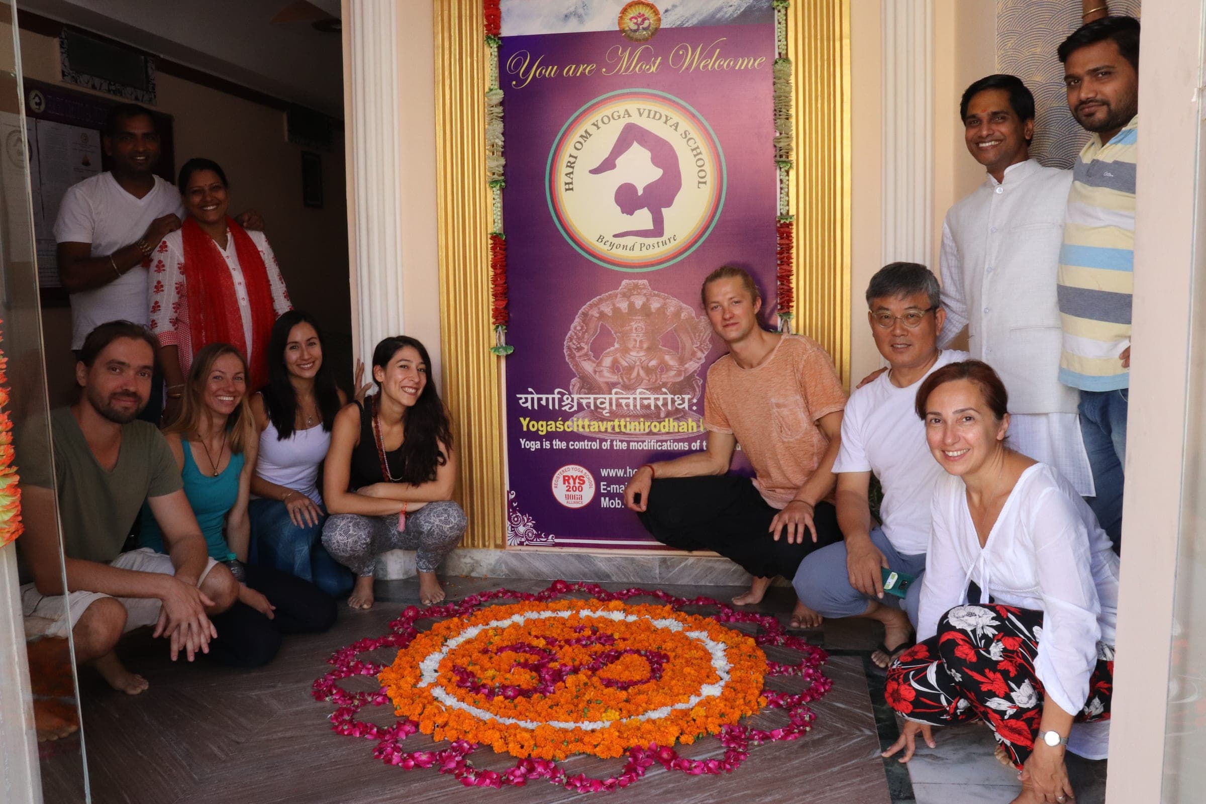 The group around a flower rangoli under the welcome banner